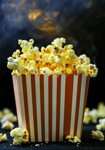 Falling popcorn in a red-white stripes box on red background